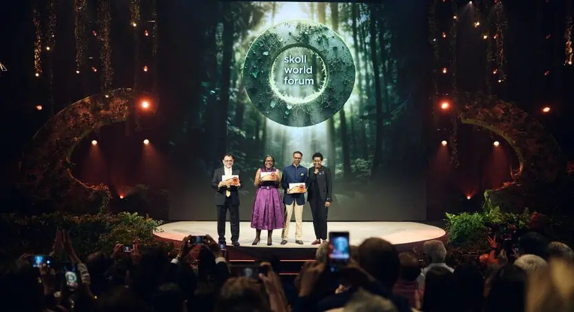 Four individuals standing on stage at Skoll World Forum in front of Skoll 2026 logo