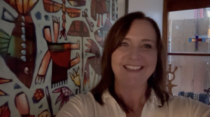 Screenshot of founder of EveryMum smiling at camera wearing white collared shirt in front of colourful walls